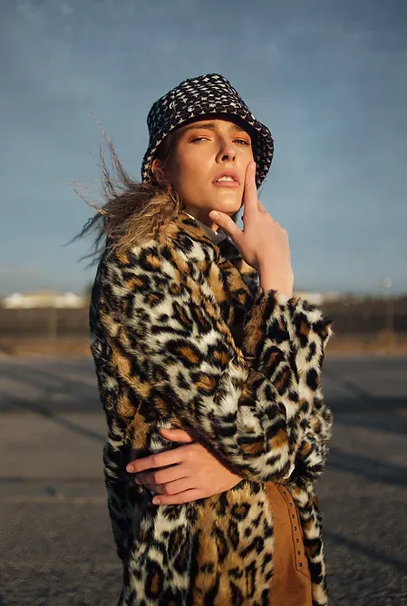 Modelo con abrigo de estampado animal y gorro pescador al atardecer
