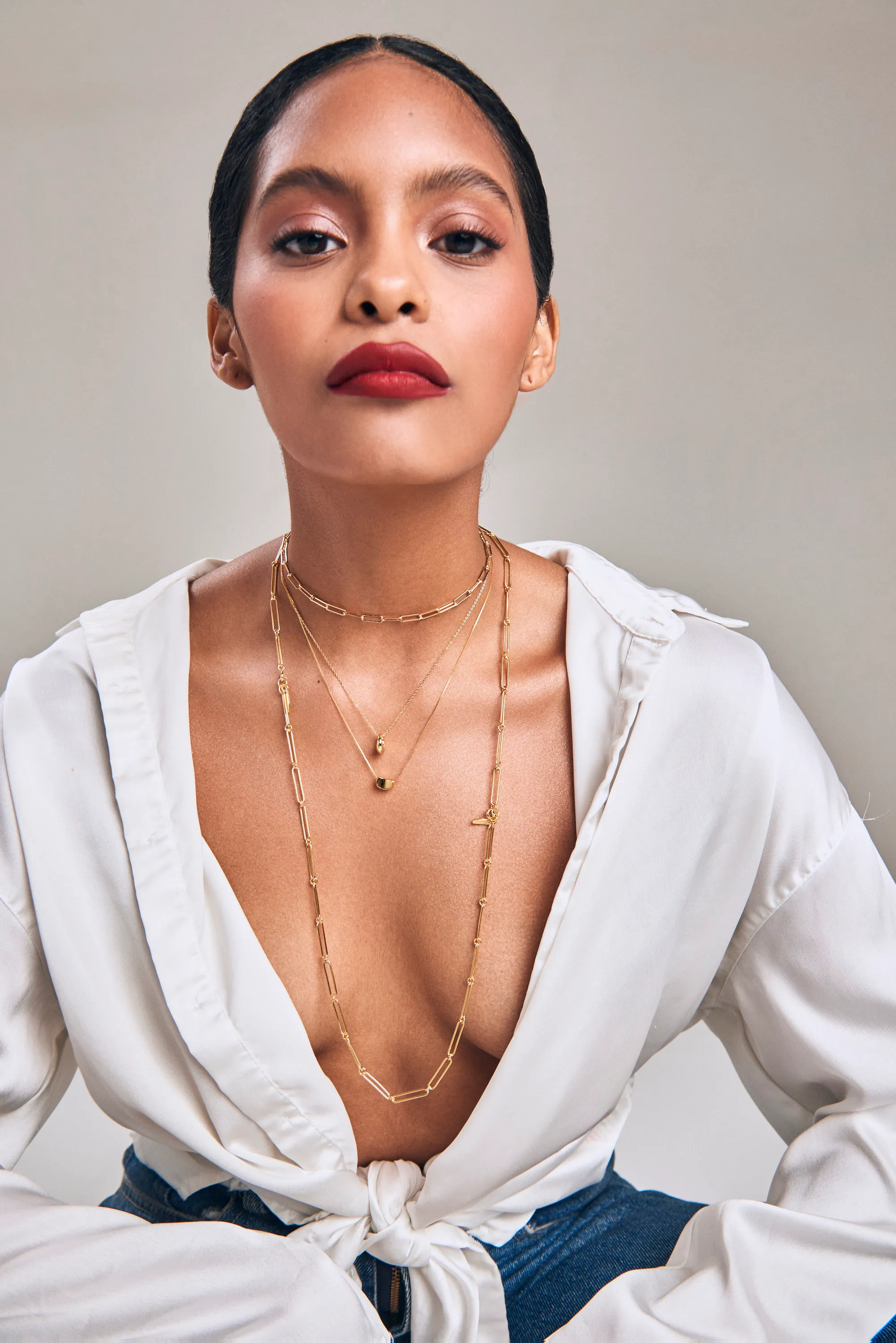 Retrato de modelo con blusa blanca anudada y collares dorados