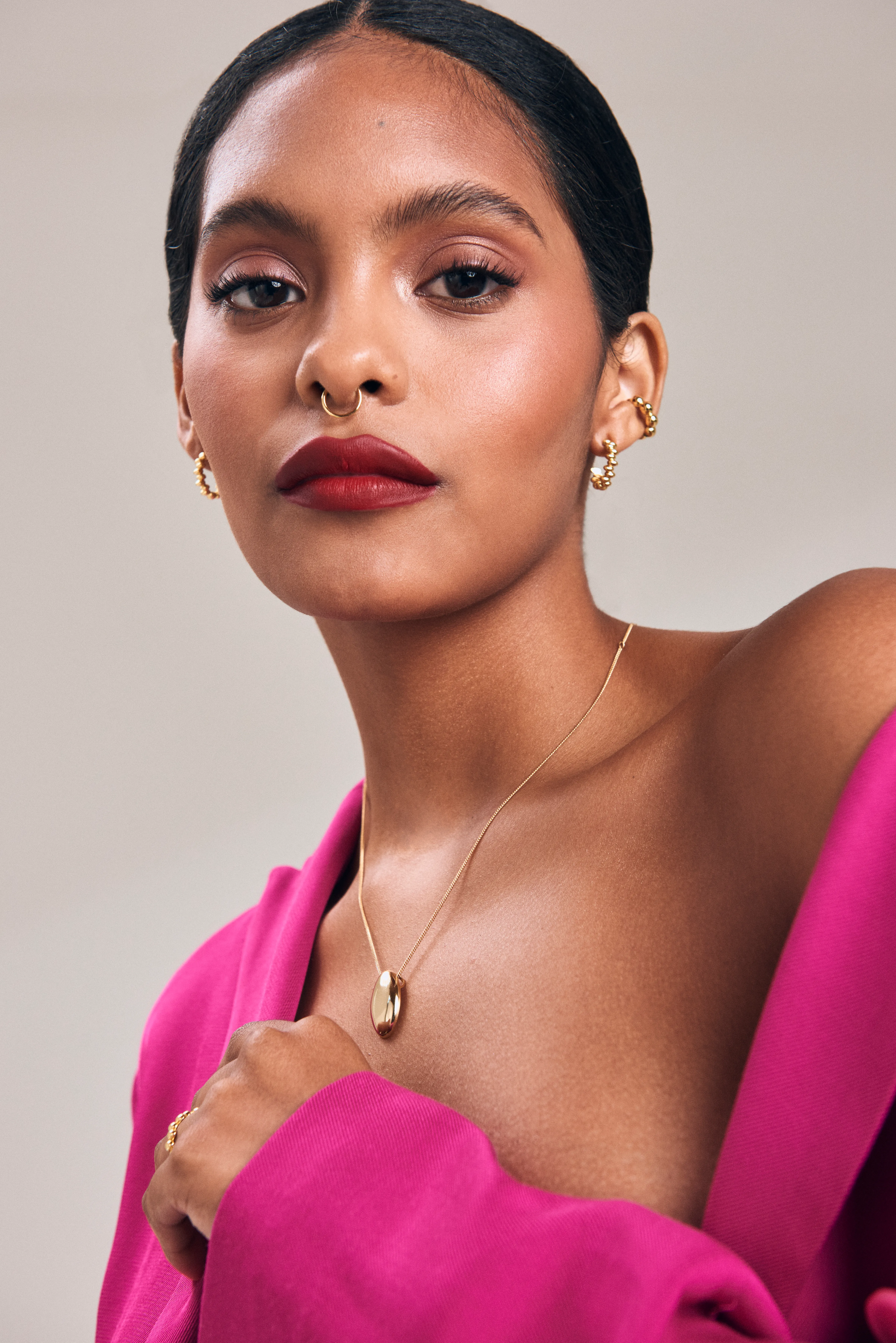 Retrato de modelo con blazer fucsia y collar dorado