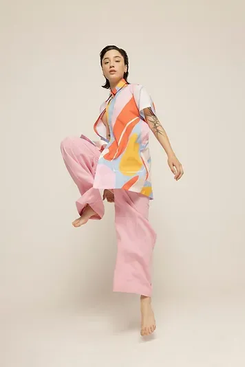 Modelo con blusa de estampado abstracto y pantalón rosado posando en movimiento