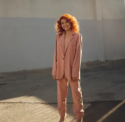 Modelo de pelo colorín con traje rosado de dos piezas junto a un muro al sol