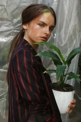 Modelo con blazer a rayas sosteniendo una planta en un macetero blanco