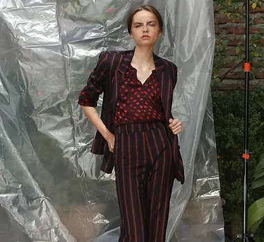Modelo con traje a rayas frente a un plástico translúcido
